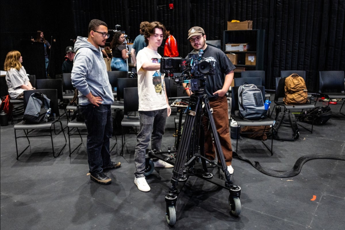 Several people crowd around a large camera