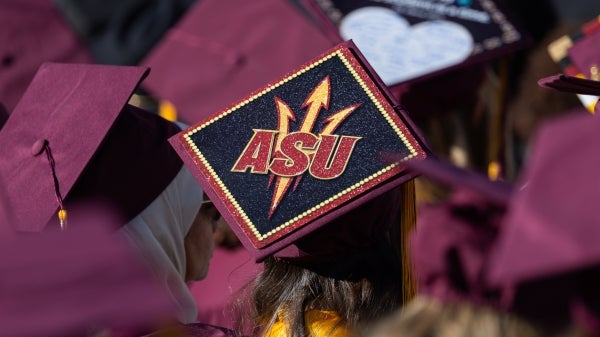 A person's graduation cap is decorated with a pitchfork and ASU.