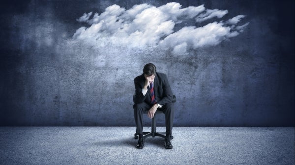 Person in a business suit seated in a chair with their head hung low.