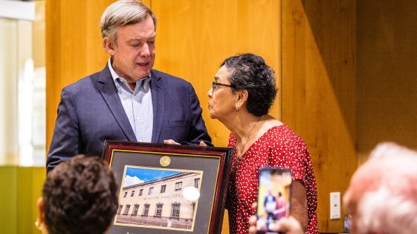 A man hands a framed photo of a post office to a woman