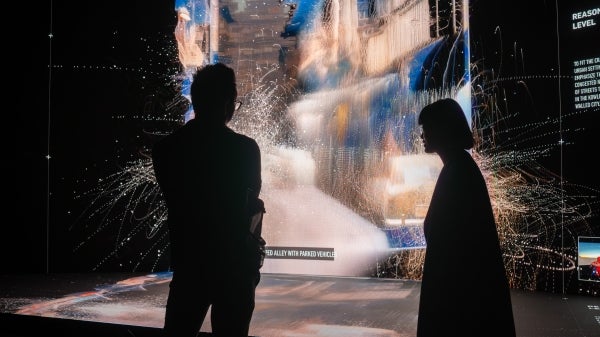 Two people looking at an art instillation; it is dark but you can see their silhouettes against the lit-up art