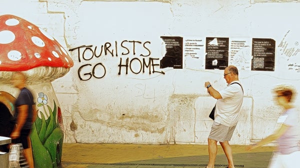 graffiti on a wall says "tourists go home"