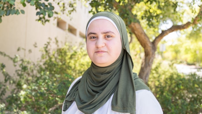 Graduating ASU student Dahlia Horani stands next to Ross-Blakley Hall on the ASU Tempe campus, with greenery in the background. Photo by Meghan Finnerty/ASU.